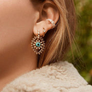 woman wearing gold and blue pierced earrings
